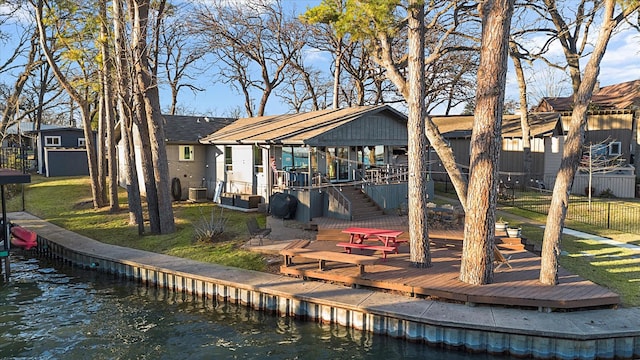 back of house with a residential view, stairs, fence, a deck with water view, and a yard