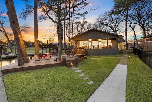 yard at dusk featuring a wooden deck and fence