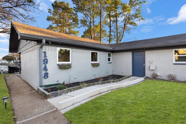 exterior space featuring brick siding, a front yard, and fence