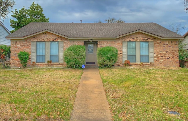 ranch-style home featuring brick siding, a front lawn, and a shingled roof