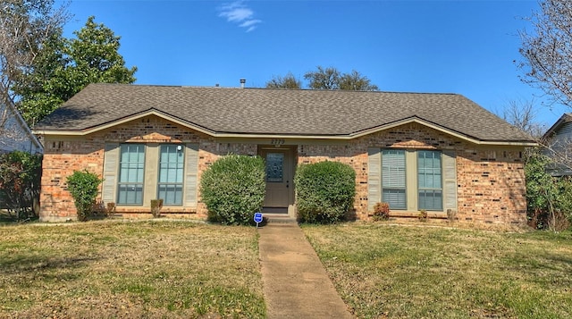 view of front of house featuring brick siding, a shingled roof, and a front yard