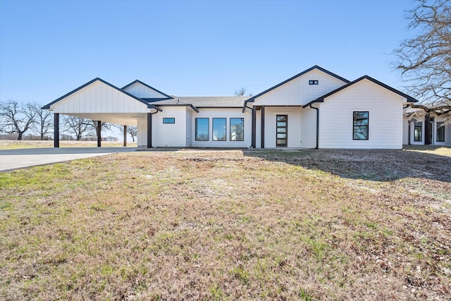 modern farmhouse featuring concrete driveway, an attached carport, and a front yard