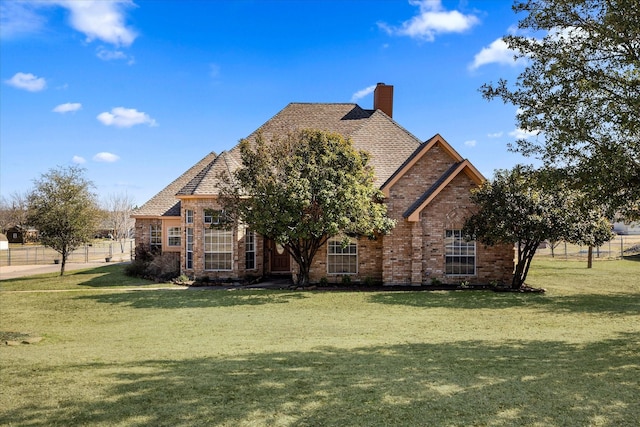 view of front of property with brick siding, a front lawn, a chimney, and a shingled roof