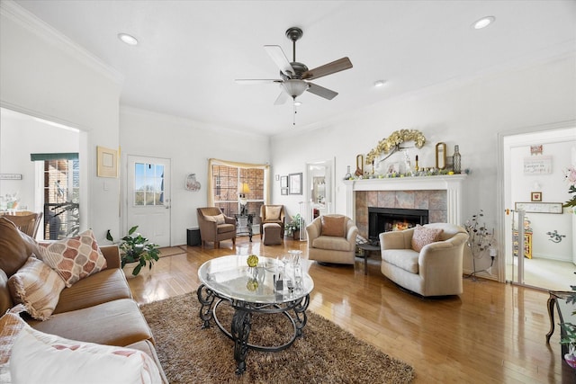 living room featuring ceiling fan, ornamental molding, light wood-style floors, a fireplace, and recessed lighting