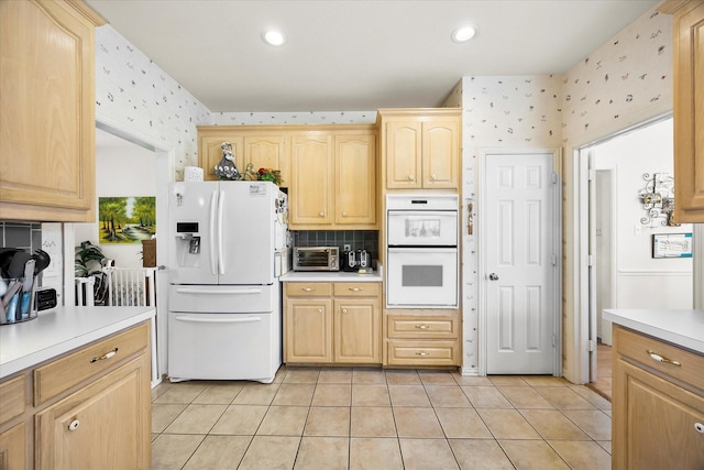 kitchen featuring light countertops, light brown cabinets, light tile patterned flooring, white appliances, and wallpapered walls