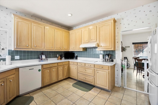 kitchen with white appliances, under cabinet range hood, wallpapered walls, and light brown cabinetry