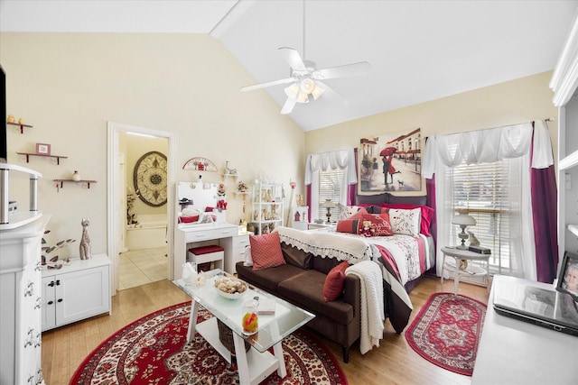 bedroom with high vaulted ceiling, connected bathroom, light wood-style flooring, and a ceiling fan