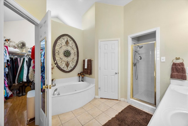 full bath featuring a stall shower, a walk in closet, a garden tub, and tile patterned floors