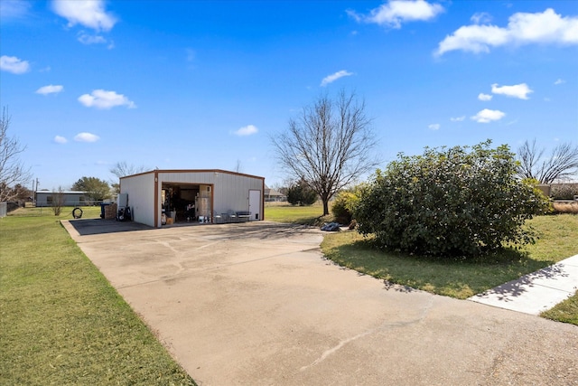 exterior space featuring concrete driveway, a detached garage, a lawn, and an outdoor structure