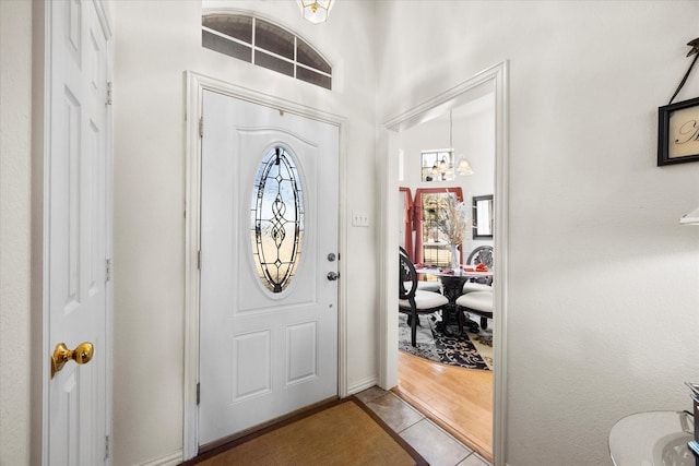 tiled foyer entrance with a chandelier