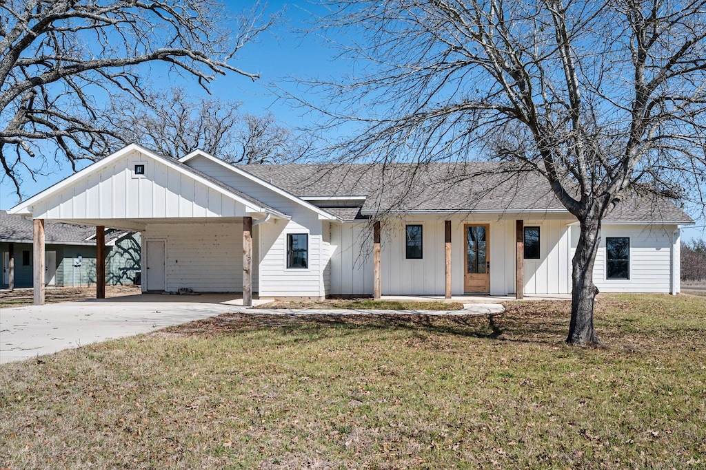 modern farmhouse style home featuring concrete driveway, a front lawn, board and batten siding, and roof with shingles