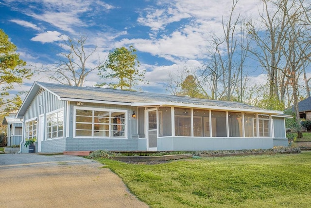 view of front of home with a sunroom, a front lawn, and brick siding