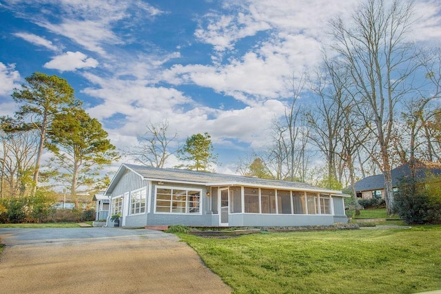 ranch-style house featuring driveway, a sunroom, and a front yard