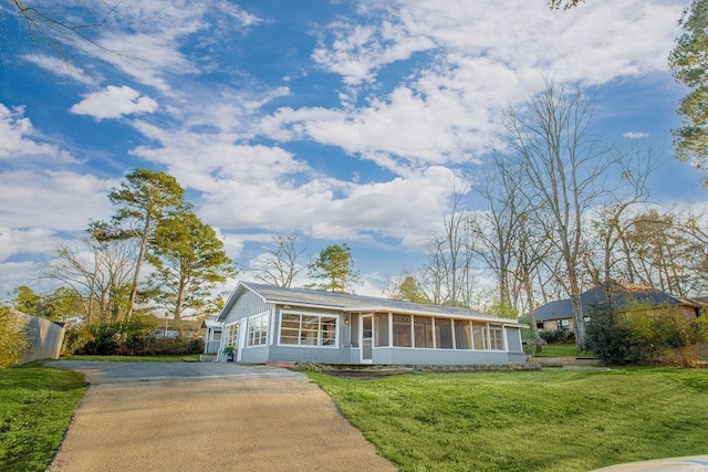 ranch-style house with driveway, a sunroom, and a front yard