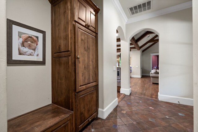 hallway with ornamental molding, arched walkways, visible vents, and baseboards