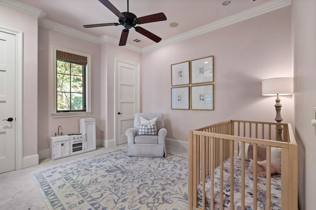 bedroom with a crib, visible vents, baseboards, ornamental molding, and carpet