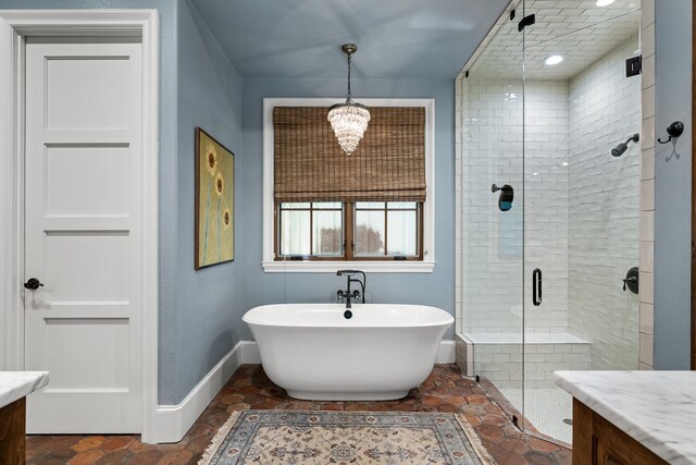 full bath featuring a stall shower, baseboards, a freestanding tub, and vanity