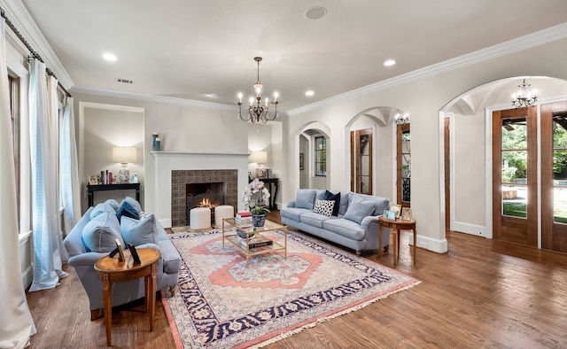 living room with ornamental molding, visible vents, a notable chandelier, and wood finished floors