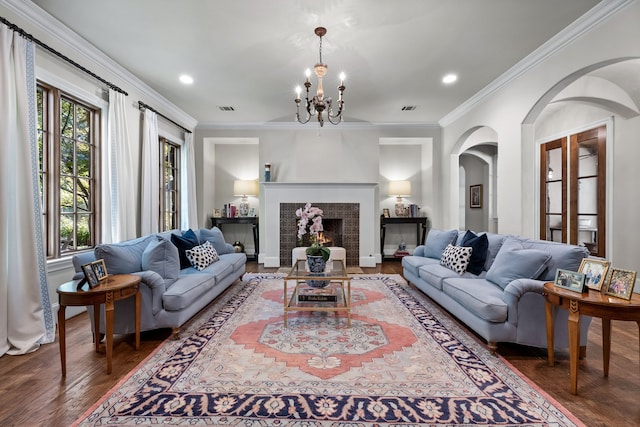 living room with ornamental molding, visible vents, a lit fireplace, and wood finished floors