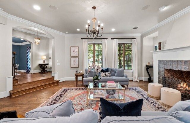 living area with arched walkways, a chandelier, and ornamental molding