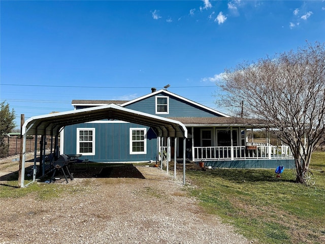 view of front of property with driveway, a sunroom, roof with shingles, a front lawn, and a detached carport