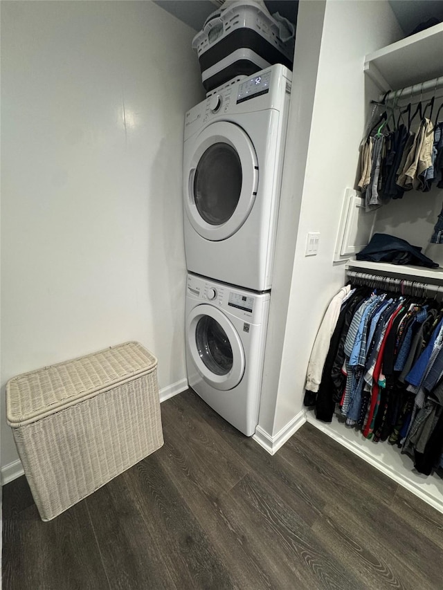 clothes washing area with laundry area, baseboards, dark wood-type flooring, and stacked washer and clothes dryer