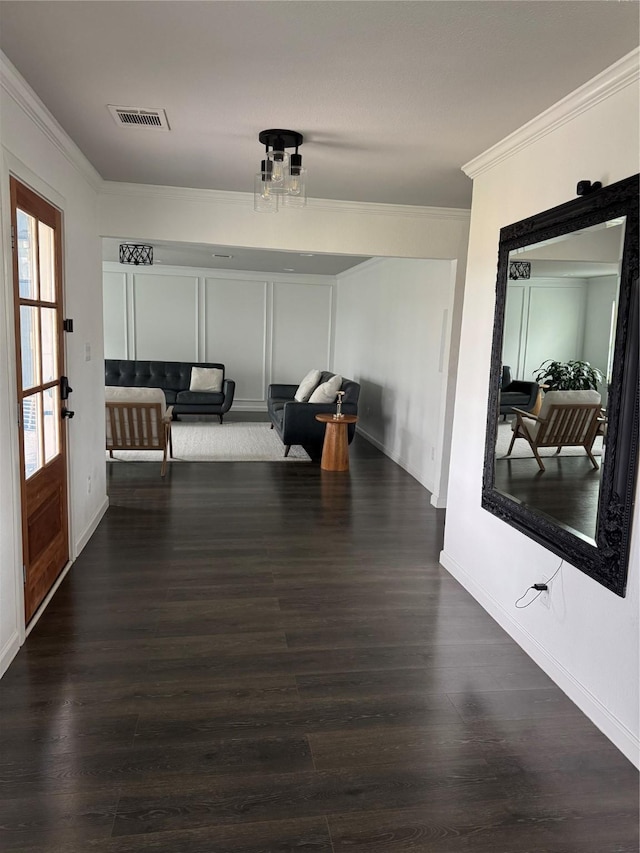 hall with wood finished floors, visible vents, and crown molding