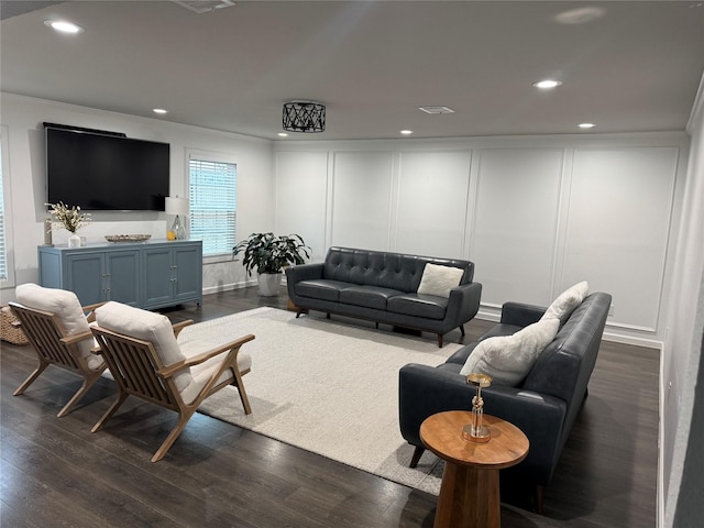 living area featuring dark wood-style floors, recessed lighting, and a decorative wall