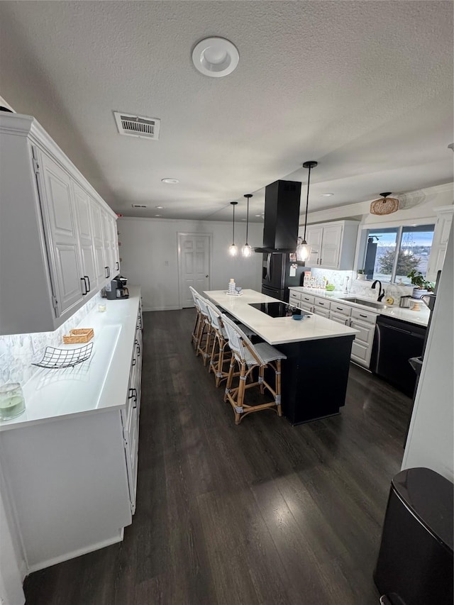 kitchen with visible vents, dark wood-type flooring, a center island, light countertops, and ventilation hood