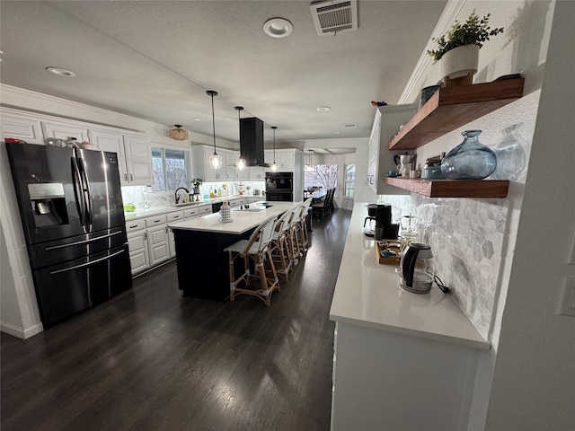 kitchen with black appliances, island exhaust hood, visible vents, and a healthy amount of sunlight