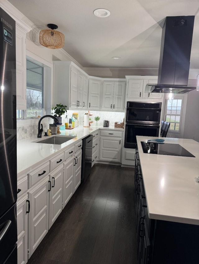 kitchen with island range hood, a sink, white cabinets, light countertops, and black appliances