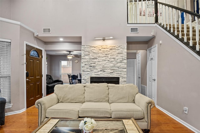 living area with baseboards, a fireplace, visible vents, and wood finished floors