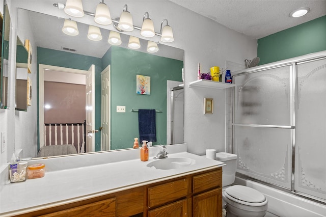 bathroom featuring a textured ceiling, toilet, shower / bath combination with glass door, visible vents, and vanity