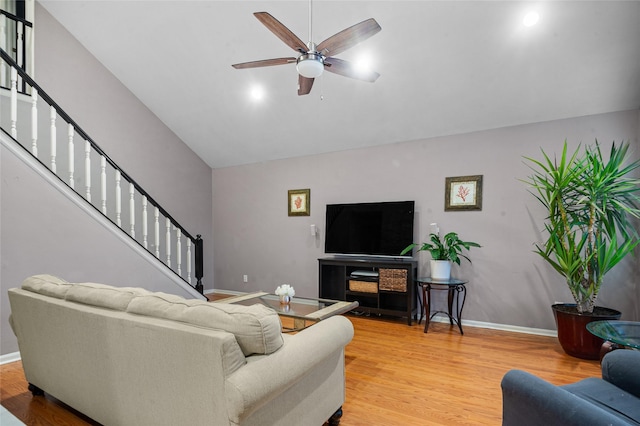 living room featuring stairs, light wood-type flooring, a ceiling fan, and baseboards