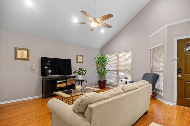 living area with high vaulted ceiling, light wood finished floors, baseboards, and a ceiling fan