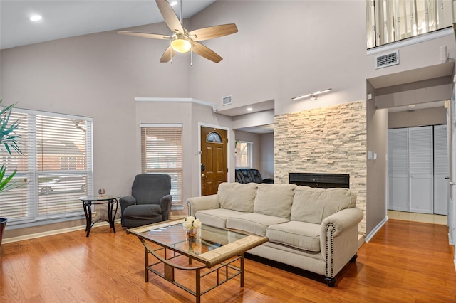 living room with light wood-type flooring, visible vents, a fireplace, and ceiling fan