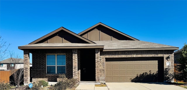 view of front of house with driveway, a garage, roof with shingles, fence, and brick siding