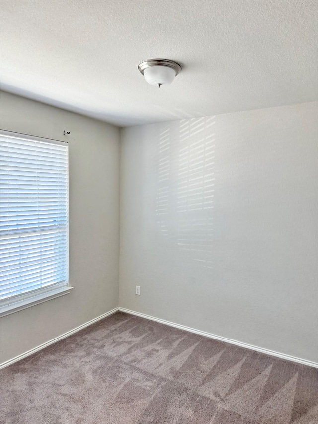 carpeted empty room with a textured ceiling and baseboards