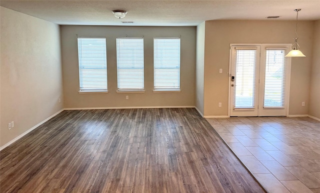 interior space featuring visible vents, a textured ceiling, baseboards, and wood finished floors