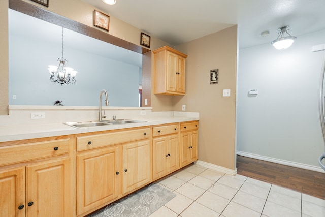 kitchen featuring light brown cabinets, a sink, baseboards, light countertops, and an inviting chandelier