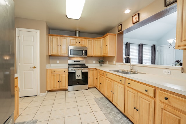 kitchen with a sink, stainless steel appliances, light brown cabinets, and light countertops