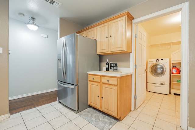 kitchen featuring washer / dryer, light brown cabinets, light tile patterned floors, and stainless steel fridge with ice dispenser