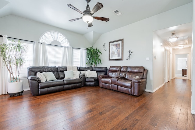 living area featuring dark wood-style flooring, lofted ceiling, visible vents, ceiling fan, and baseboards