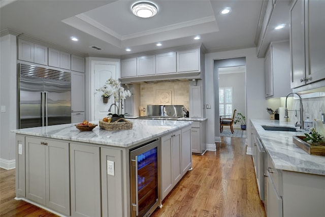 kitchen featuring beverage cooler, a tray ceiling, built in refrigerator, and a sink