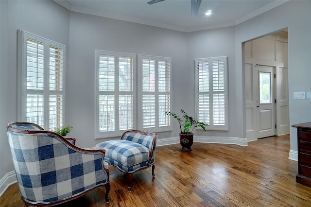 living area featuring ornamental molding, wood finished floors, a ceiling fan, and baseboards