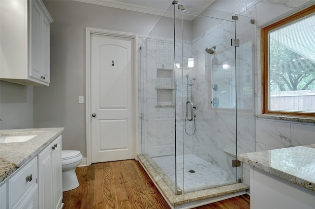 bathroom featuring a shower stall, crown molding, wood finished floors, and vanity