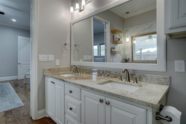 bathroom with crown molding, a sink, and wood finished floors