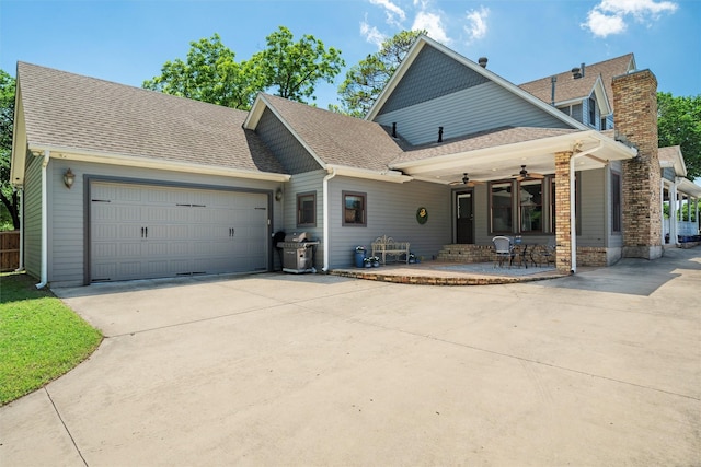 view of front of house with driveway, a garage, a ceiling fan, and roof with shingles