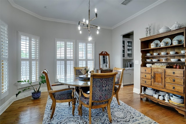 dining area featuring a wealth of natural light, crown molding, visible vents, and wood finished floors