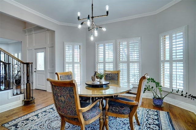 dining room featuring baseboards, ornamental molding, wood finished floors, stairs, and a notable chandelier